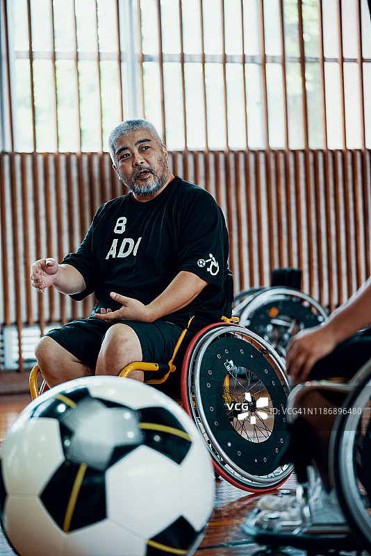 从事轮椅足球这项包容性运动的人们正在体育馆里交谈图片素材