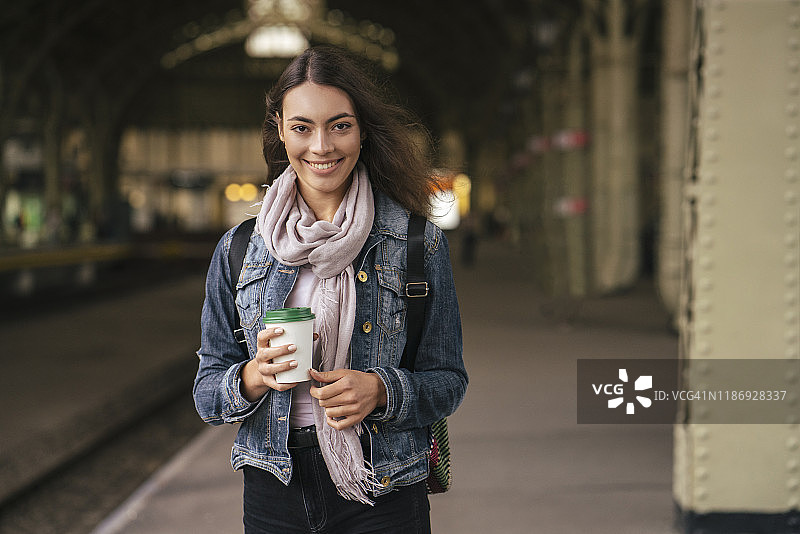 年轻的女旅客带着咖啡去火车站图片素材