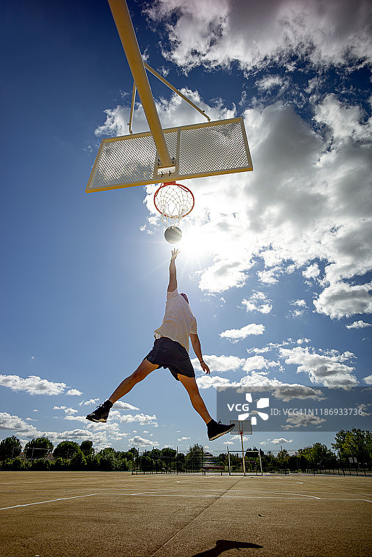 一个人在黄色的球场上打篮球，扣篮图片素材