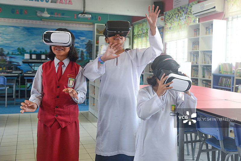 亚洲女学生在学校的教室里使用虚拟现实眼镜图片素材
