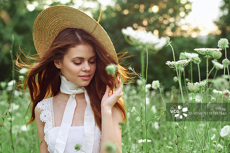 美丽温柔的女孩戴着草帽在一片花丛中图片素材
