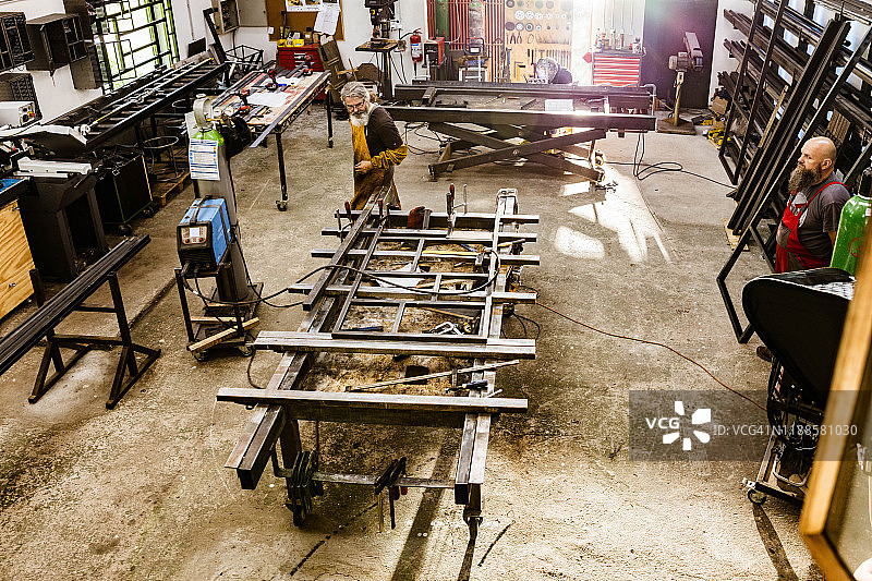 上图为钢铁工人在车间内建造的结构上工作。图片素材