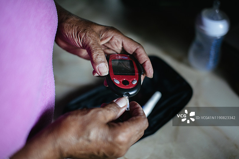 老年黑人妇女使用糖尿病家庭检测试剂盒"n图片素材