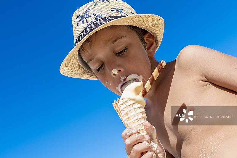 有趣的小男孩在热带海滩上吃冰淇淋，毛里求斯图片素材