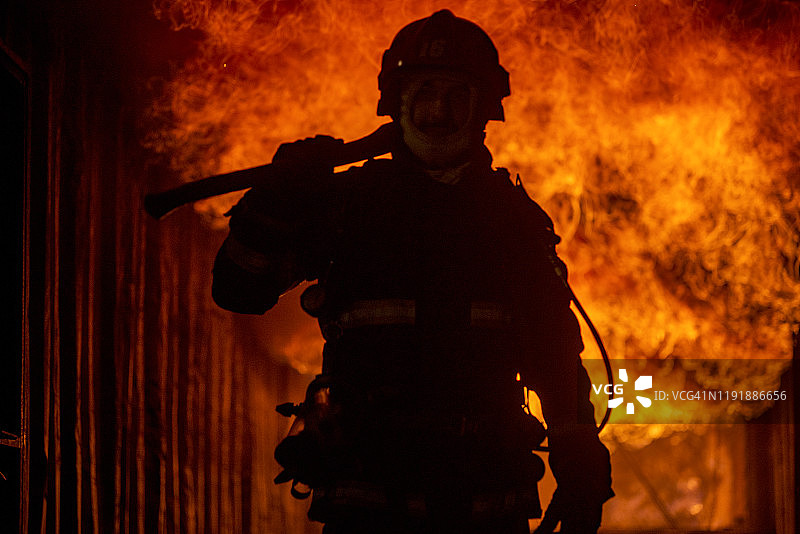 消防队员与熊熊燃烧的木材大火搏斗的剪影图片素材