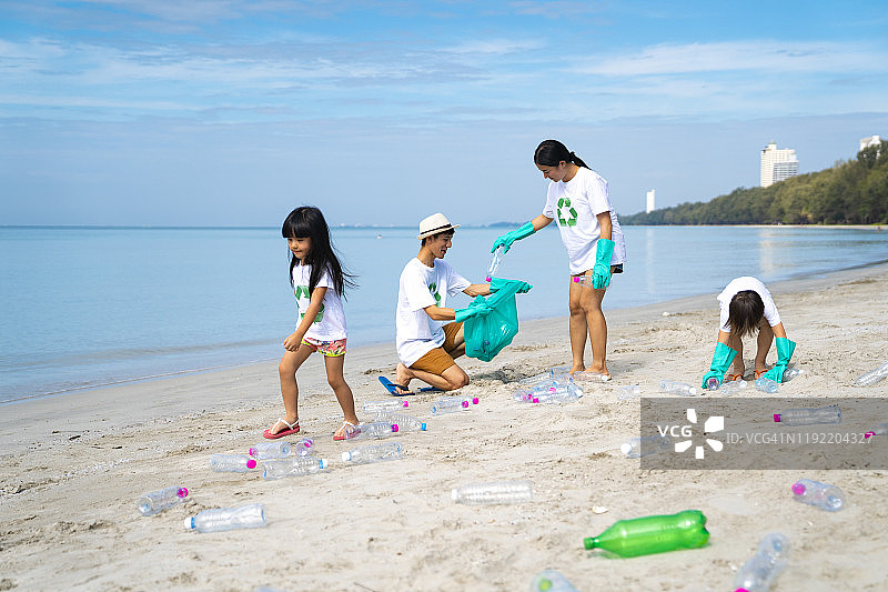 父母和孩子们在海滩上捡垃圾。图片素材