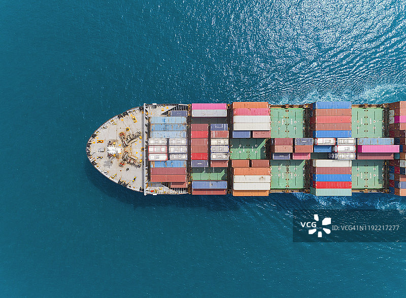 在海港或集装箱仓库鸟瞰集装箱船，工作起重机桥装集装箱用于物流，进出口，运输或运输。图片素材