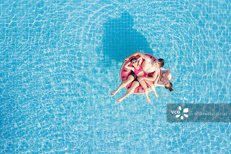 鸟瞰图的幸福亚洲家庭在游泳池，在水里玩，父亲，母亲和女儿享受水上公园在度假村，暑假，度假概念图片素材