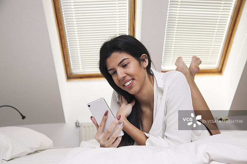 一名女子在床上使用智能手机图片素材