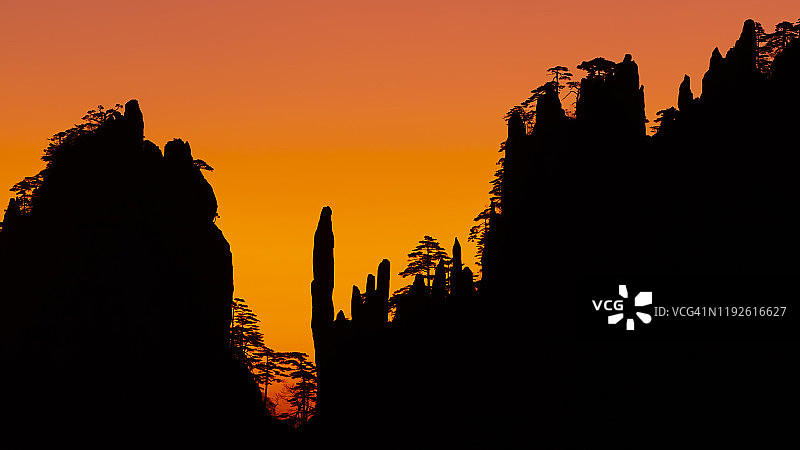 多彩的黎明天空映衬着黄山山峰的剪影图片素材