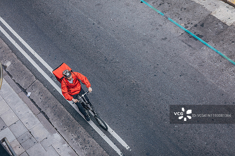 披萨外卖员骑着自行车在城市的街道上图片素材