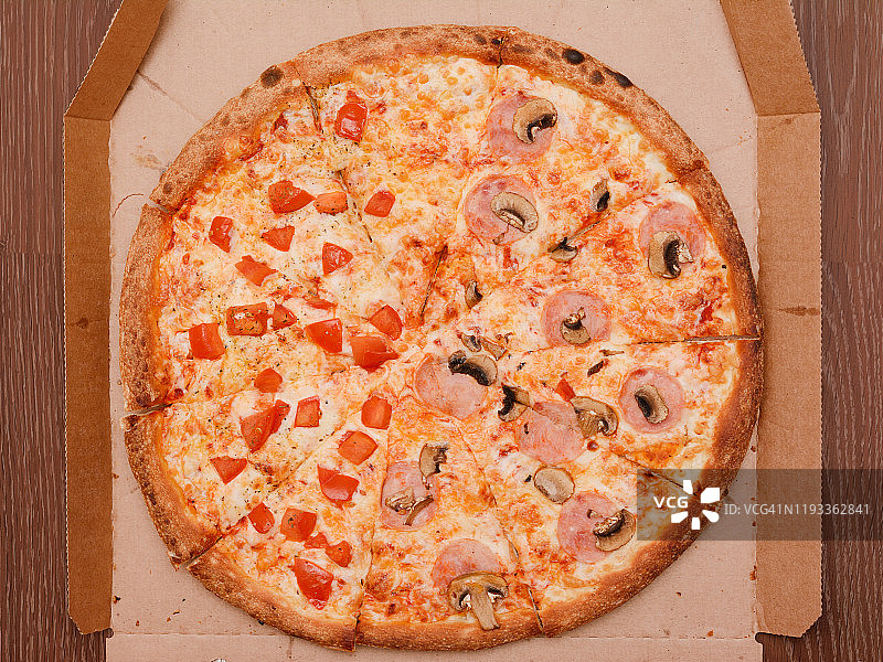 纸板盒里的圆圆的大披萨。从上往下看图片素材
