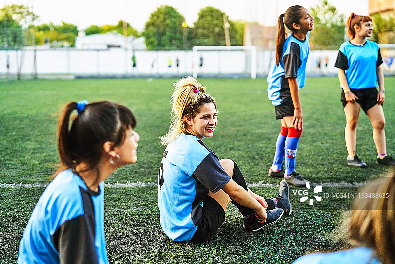 微笑的足球女孩与团队在运动场上图片素材