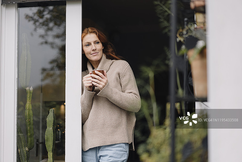 女人靠在门口，喝着咖啡图片素材