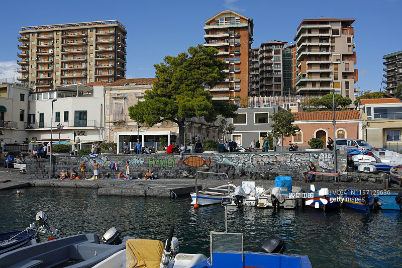 在西西里岛卡塔尼亚的San Giovanni Li Cuti码头附近，未定义的当地人和游客在晒日光浴图片素材