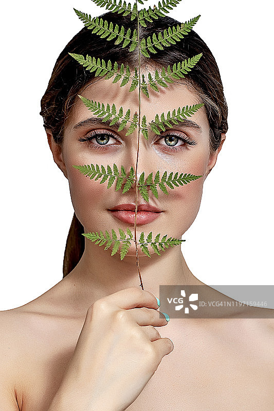 一个成年的褐发女人的肖像在一个白色的背景与绿色的蕨类植物图片素材