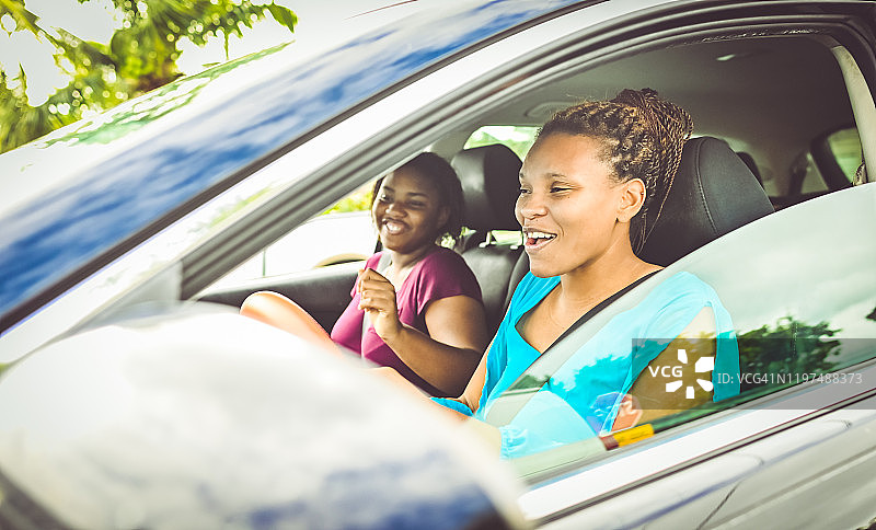 非洲裔美国妇女和十几岁的女儿坐在一辆车里开心地笑着图片素材