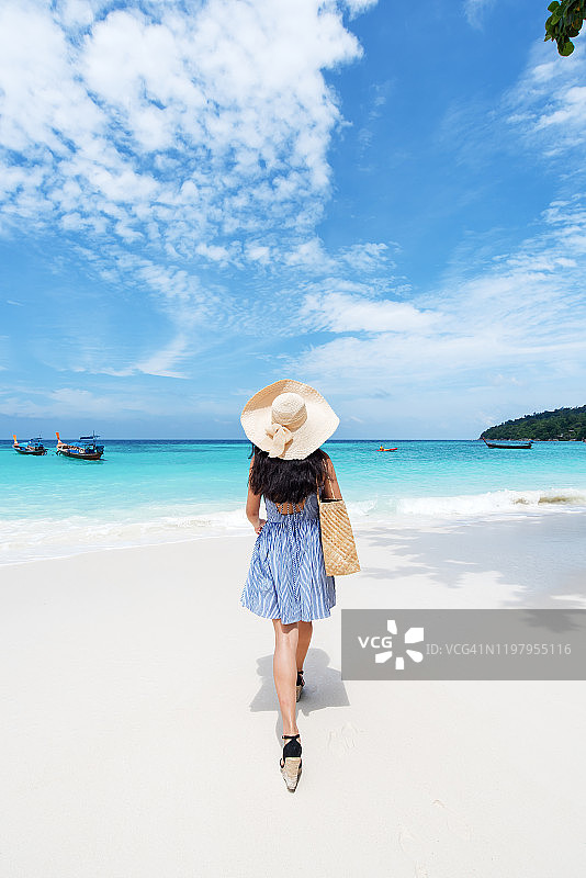 美丽的年轻女子走在热带的海滩上，穿着夏装图片素材