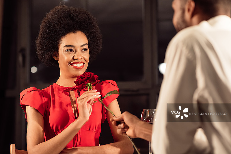 非洲裔男子在餐厅送女友红玫瑰庆祝周年图片素材