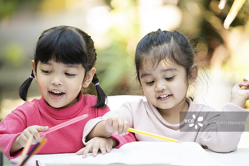 快乐两个亚洲姐妹女孩在家里一起做作业。教育的概念图片素材