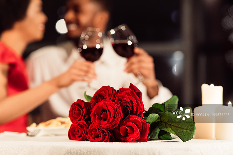 桌上放着玫瑰，陌生的配偶在餐厅喝酒图片素材