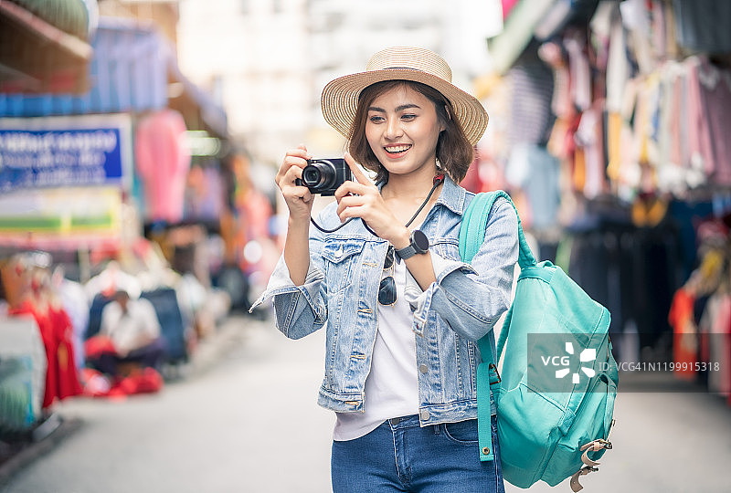 女摄影师正在用相机拍照。快乐的女人度假摄影与相机在考山路，曼谷，泰国。女孩冒险外出旅游度假摄影概念图片素材