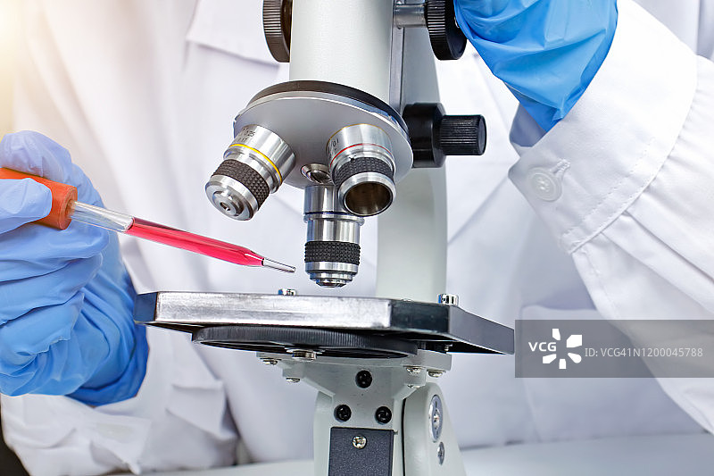 研究科学家在实验室用显微镜填充试管。图片素材