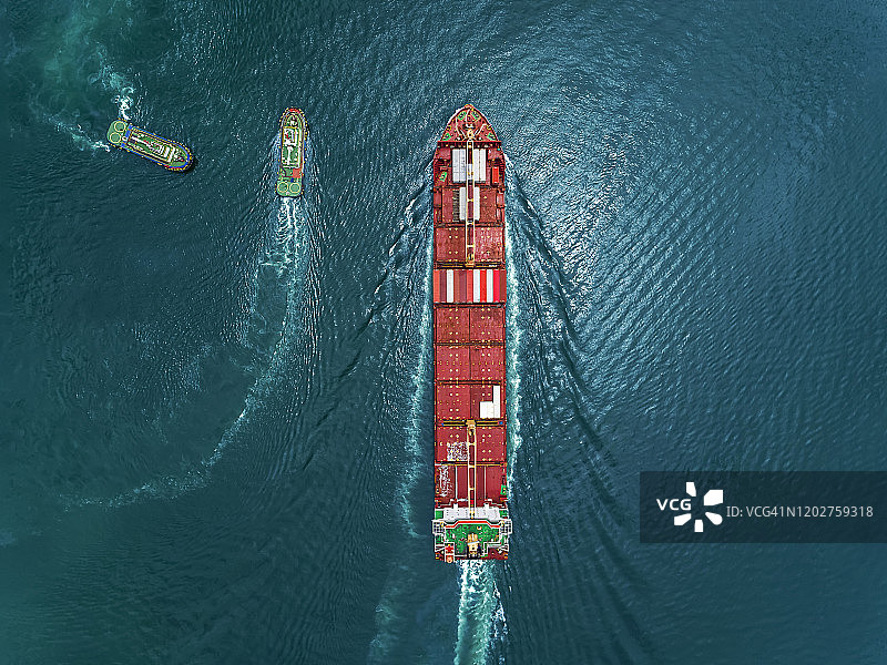 货轮鸟瞰图，两艘拖船拖着集装箱在泰国的仓库港口。图片素材