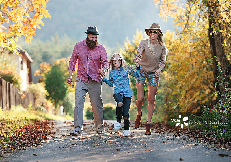 一家人带着小女儿在秋天的大自然中户外散步。图片素材