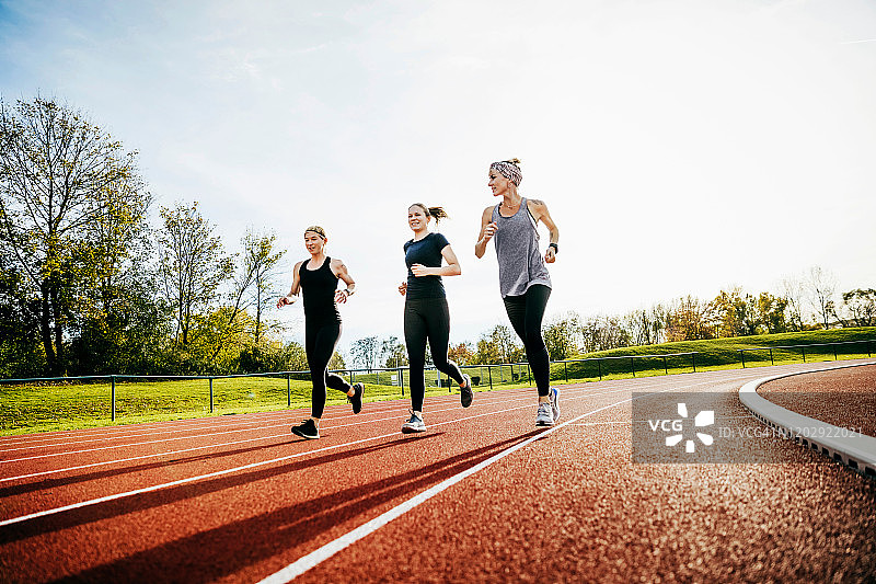 三个女人一起在跑道上跑步图片素材