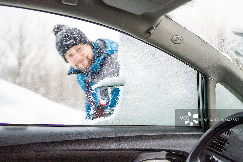 刮着车窗外的冰雪，男人正看着车窗外图片素材