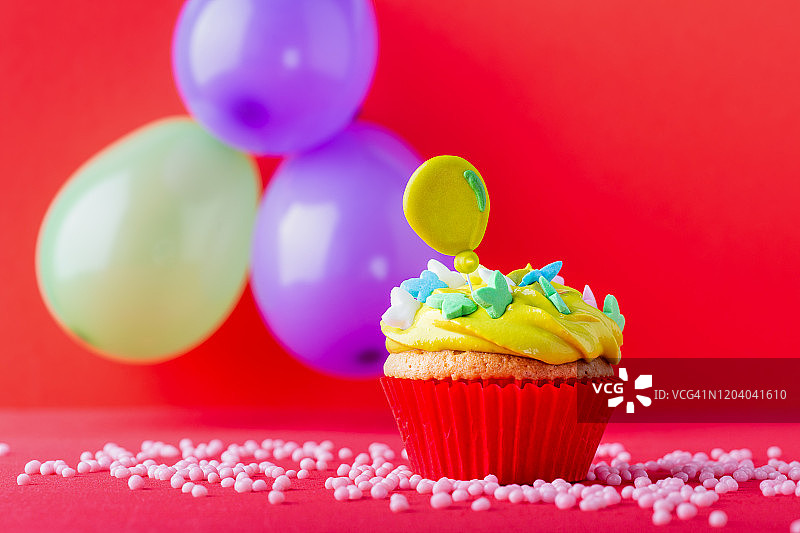 食物庆典，一个纸杯蛋糕和彩色气球在红色的背景图片素材
