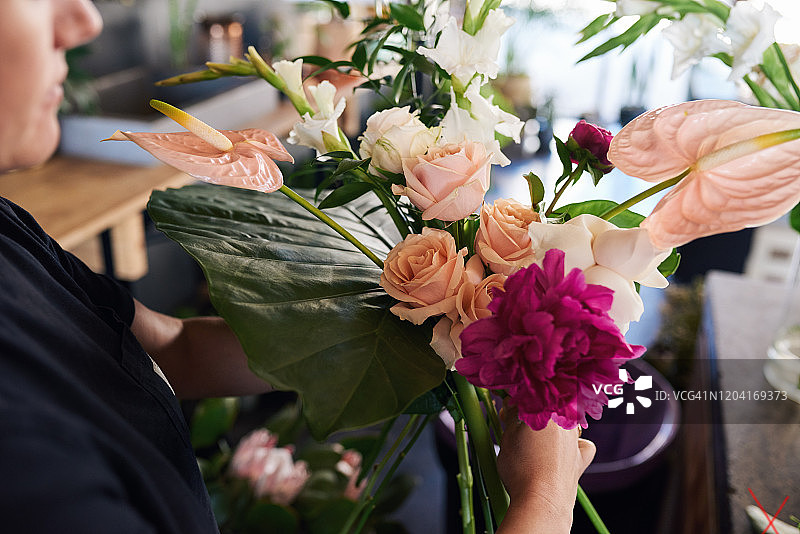 女花商在她的商店里做一个混合的花束图片素材