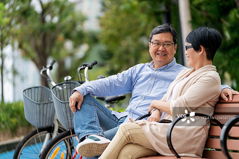 一对成熟的亚洲夫妇在公园长椅上放松图片素材