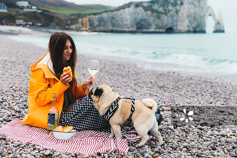 一个女人和一只狗在法国美丽的拱门附近的海滩上进行完美的野餐图片素材