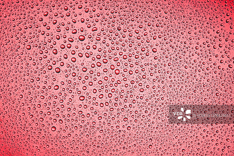 红色背景上的水滴。图片素材