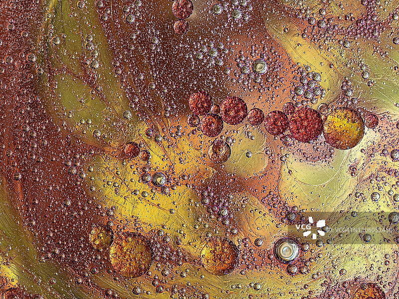 在棕色液体背景上的气泡和水滴形成的抽象形状和纹理的完整框架。图片素材