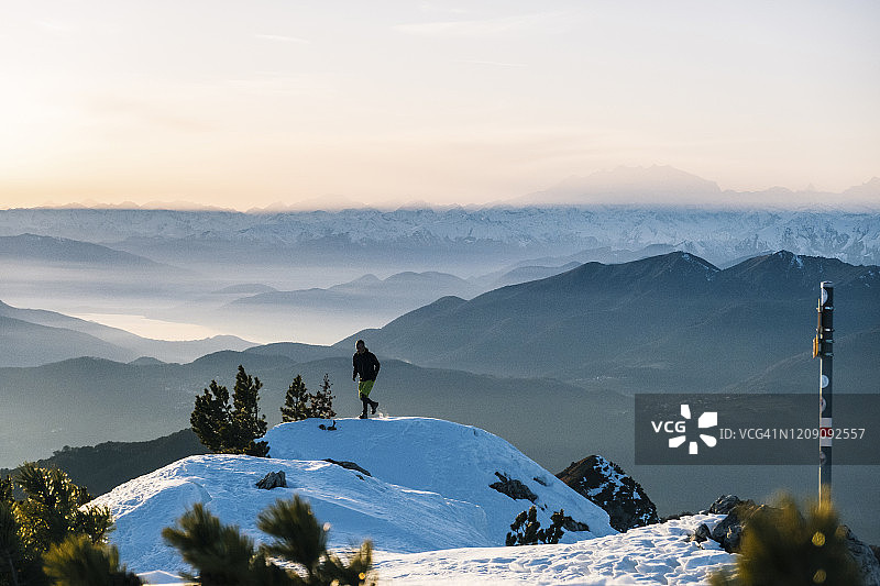 黎明时分，一名徒步运动员爬上雪山的山脊图片素材
