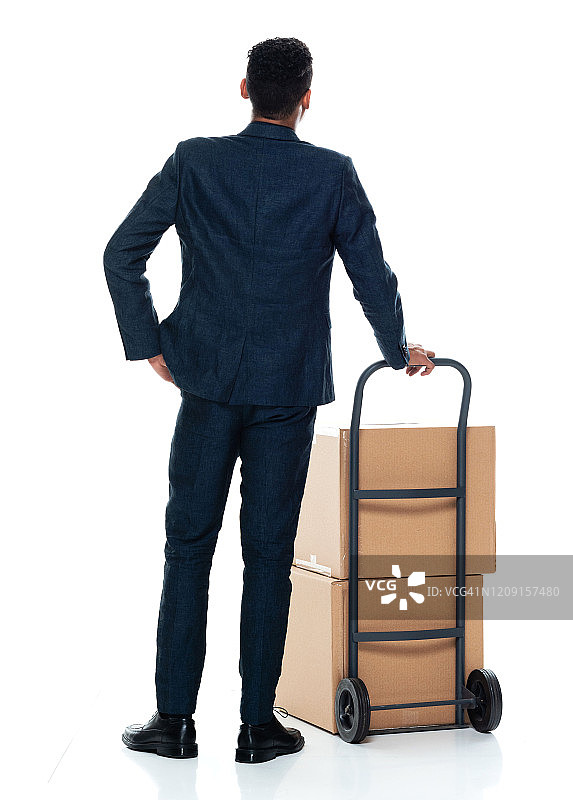 非裔美籍年轻男性送货员，穿着商务便服，拿着包裹，用手推车，站在白人背景前图片素材