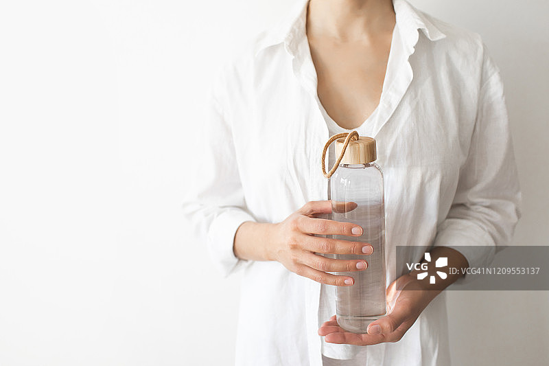 女性手握环保可重复使用的水瓶。“零浪费”。绿色和有意识的生活理念。拯救我们的星球。图片素材