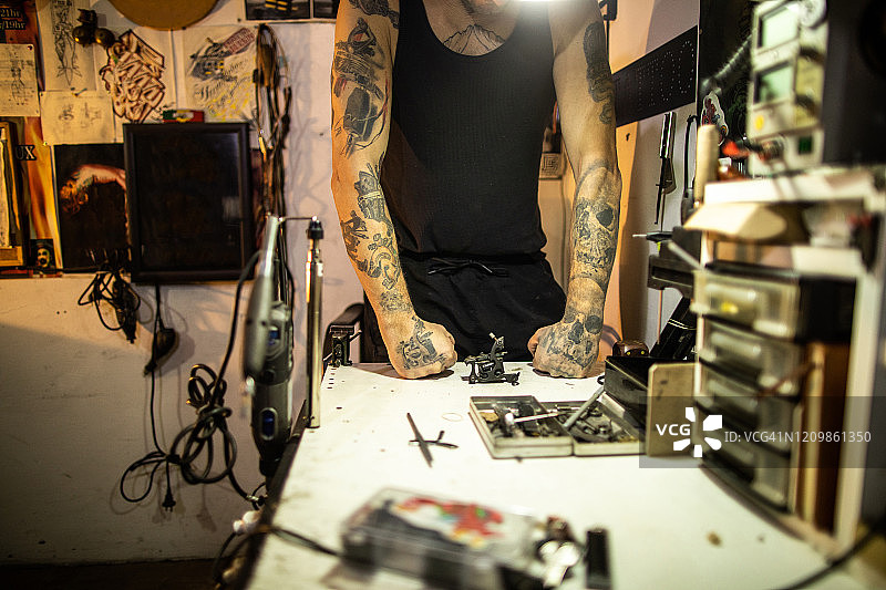 纹身艺术家站在他的工作台前，上面有纹身机图片素材