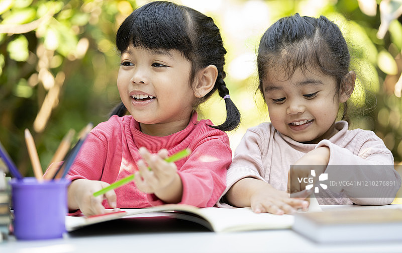 快乐两个亚洲姐妹女孩在家里一起做作业。教育的概念图片素材