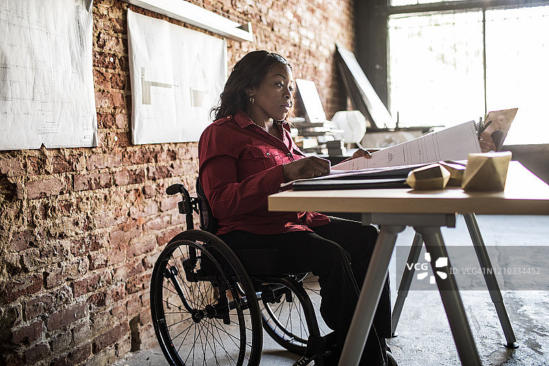 坐轮椅在办公桌前工作的女商人图片素材