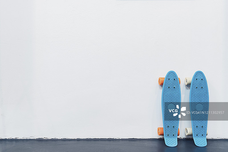 蓝色的滑板靠在白色的墙上图片素材