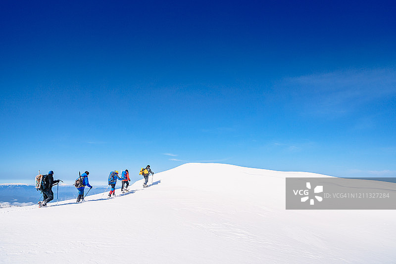 冬季，高山登山队正徒步前往这座高海拔山脉的顶峰图片素材