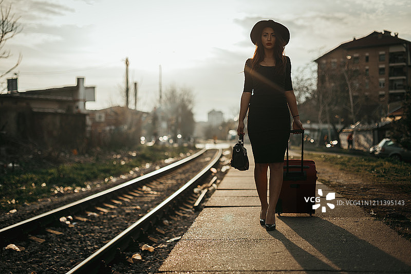 一个年轻女子带着提箱在火车站戴帽子图片素材