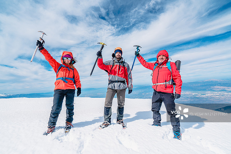 冬季，高山登山队正手持冰镐站在高海拔的山峰上图片素材