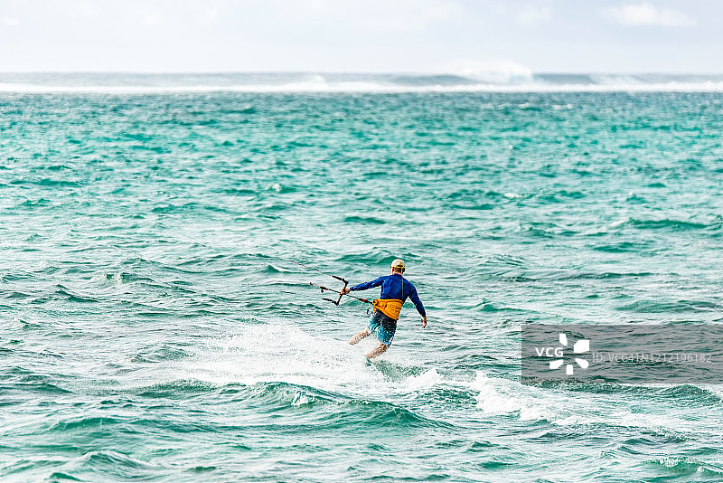 后视图的成熟男子风筝滑板在毛里求斯岛。图片素材