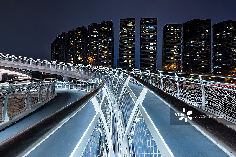 扭曲的现代未来主义大桥在夜晚被摩天大楼照亮图片素材