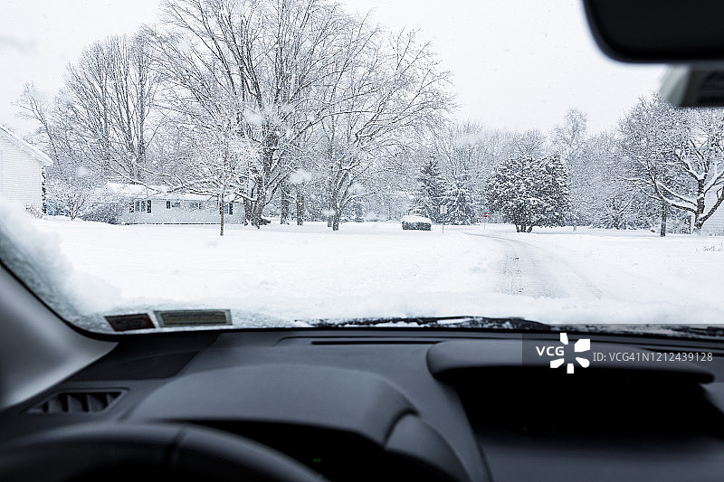 暴风雪期间，汽车在郊区住宅区街道上行驶图片素材